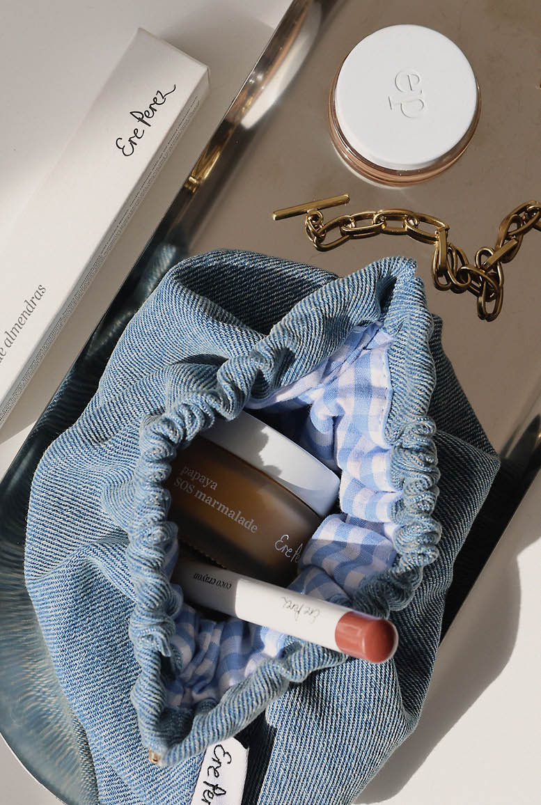 Cosmetic bag with skincare products and a lip balm on a neutral background