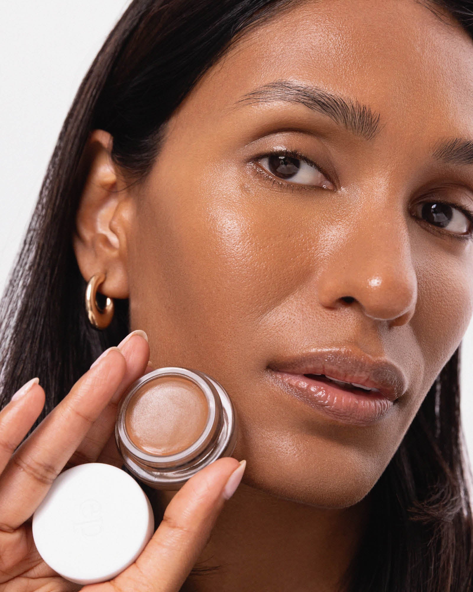 Person has applied Arnica All Cover Pot to their face with a close-up of the product. Arnica All Cover Pot in the shade dolce