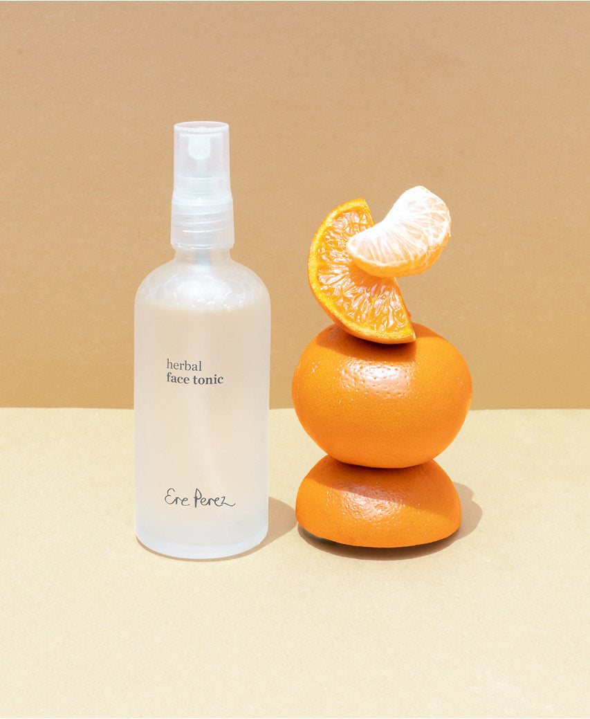 Organic herbal face tonic Ere Perez next to its star ingredient: mandarin