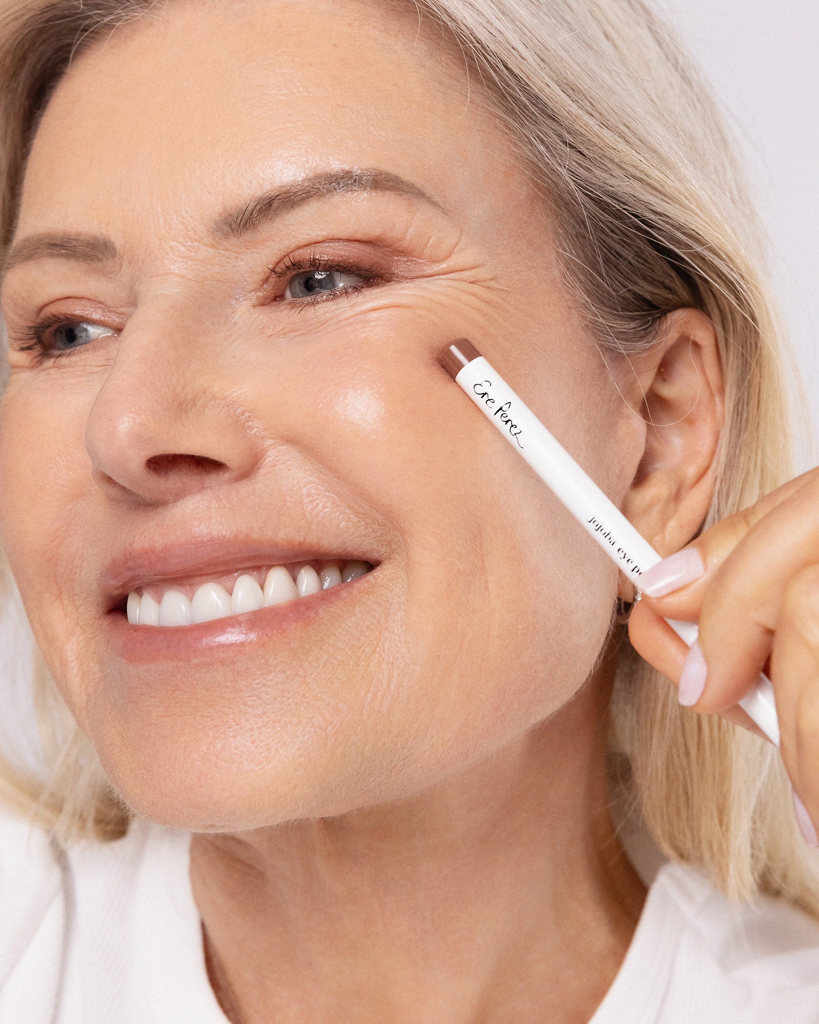 model wearing and holding jojoba eye pencil on eyes Ere Perez