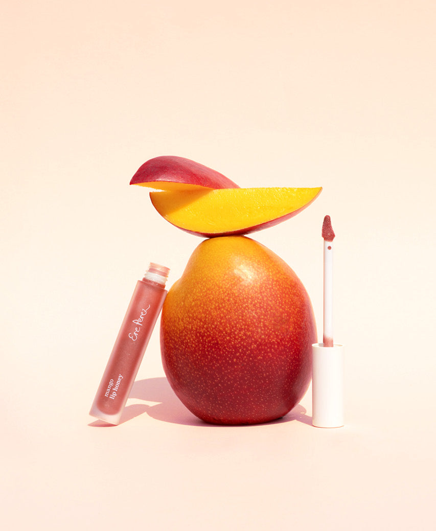 Natural mango lip honey by Ere Perez next to its star ingredient: mango
