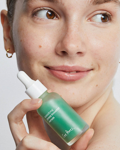 Person holding a green skincare serum bottle with a neutral background. Quandong green booster serum