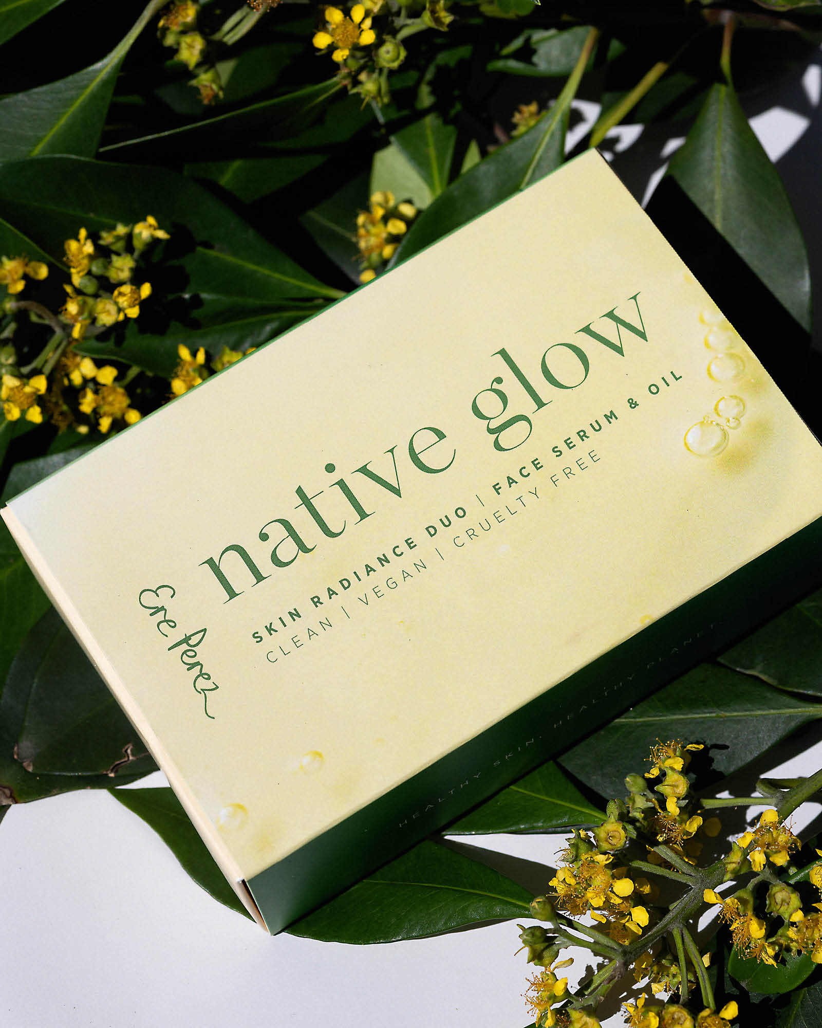 Native Glow skincare product packaging surrounded by green leaves and yellow flowers