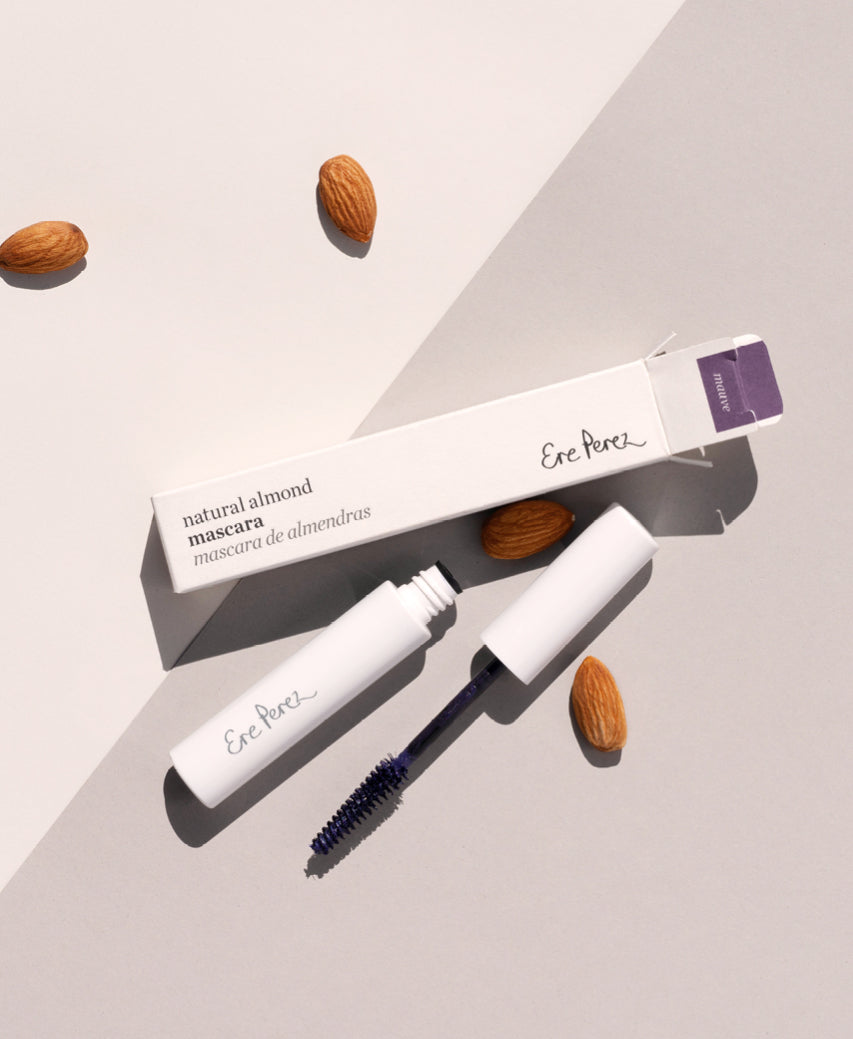 Mauve natural almond mascara by Ere Perez in its tube packaging surrounded by its star ingredient: almonds