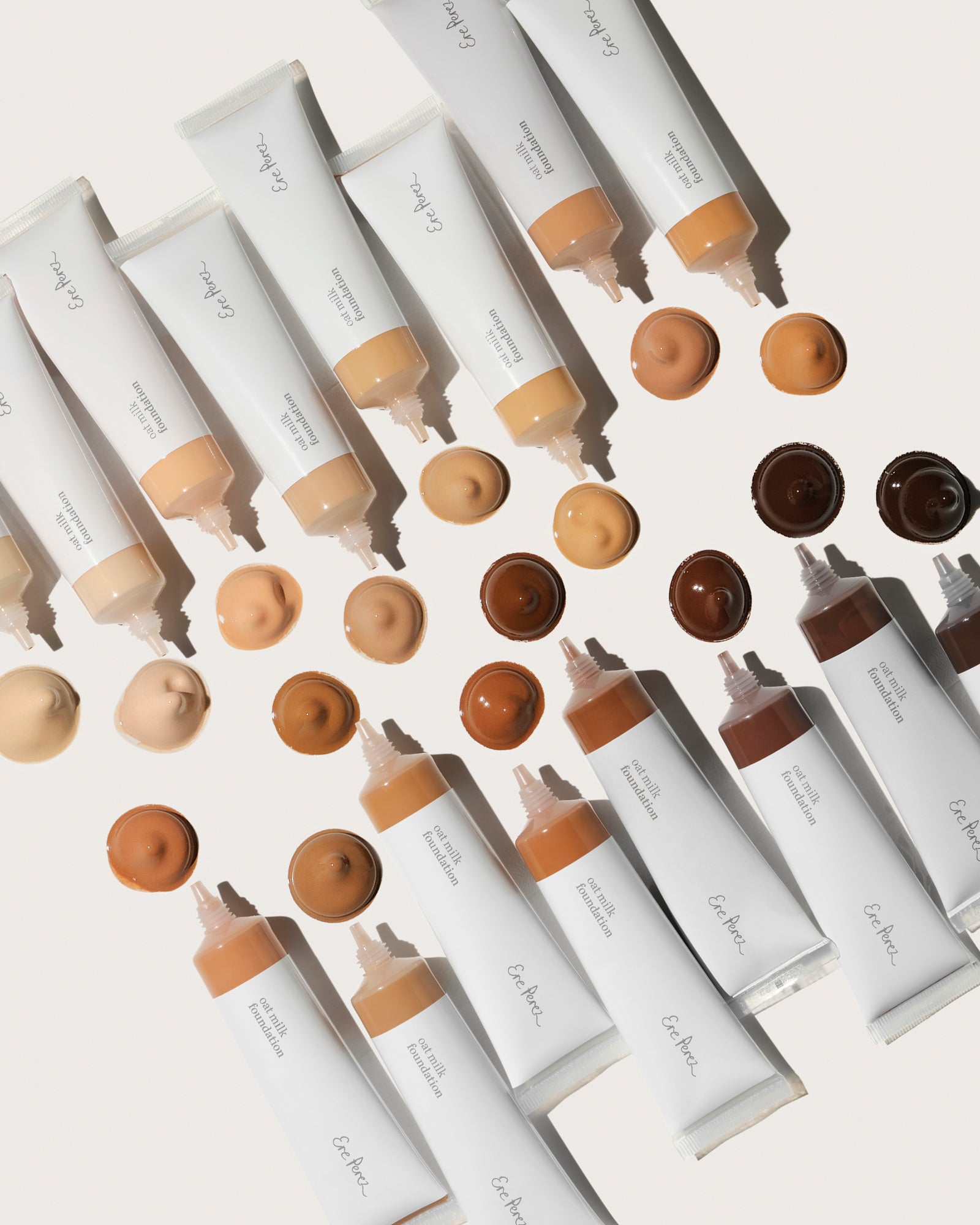 Row of cosmetic tubes with applicators and color samples on a light background