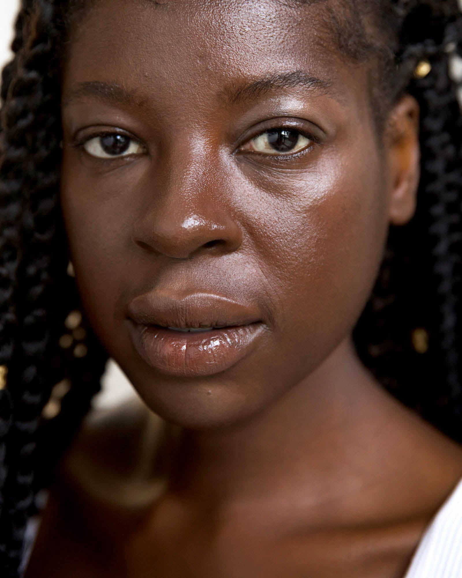 Close-up of a person with braided hair and a neutral expression