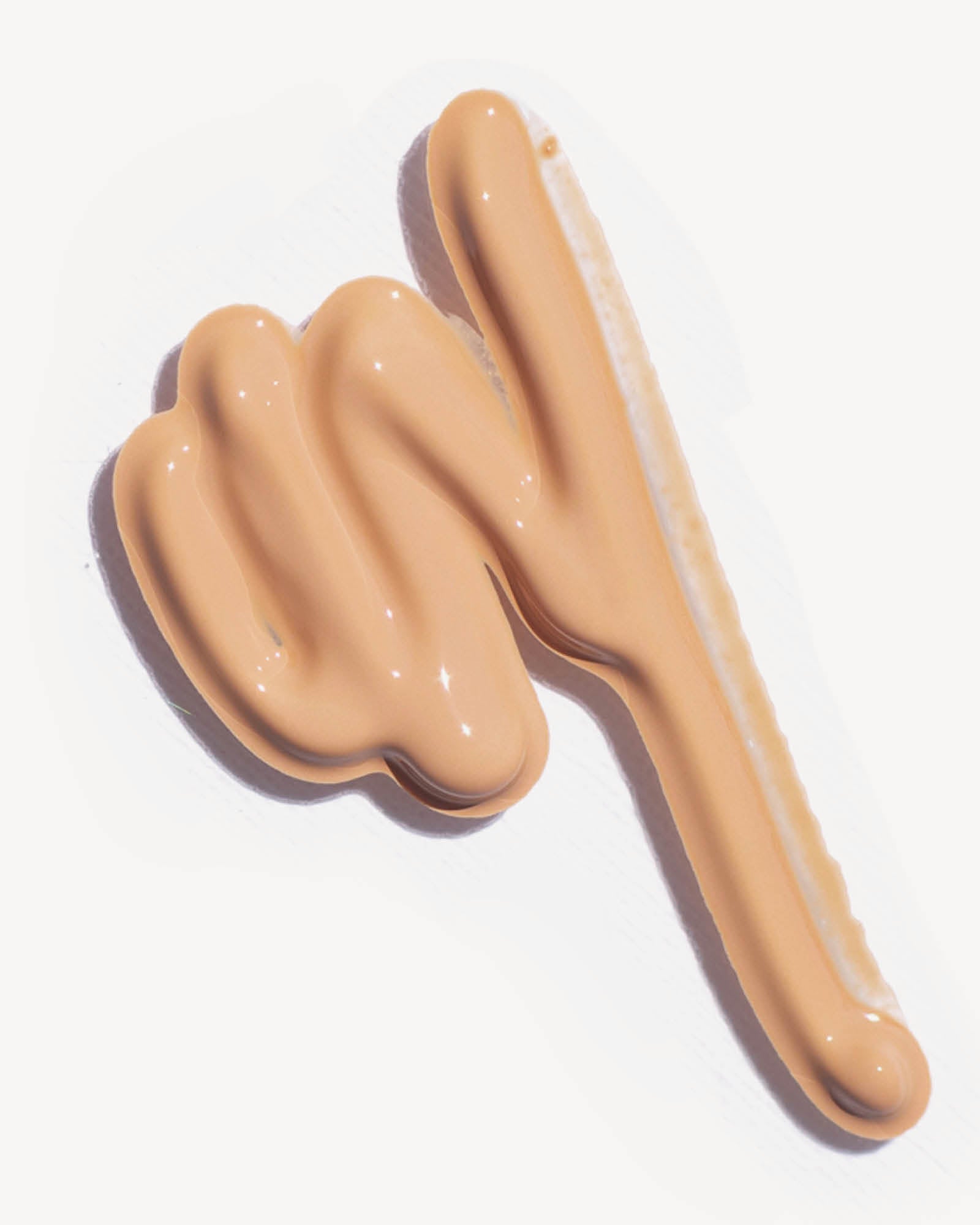 Hand-shaped makeup product with a smooth, even finish on a white background,