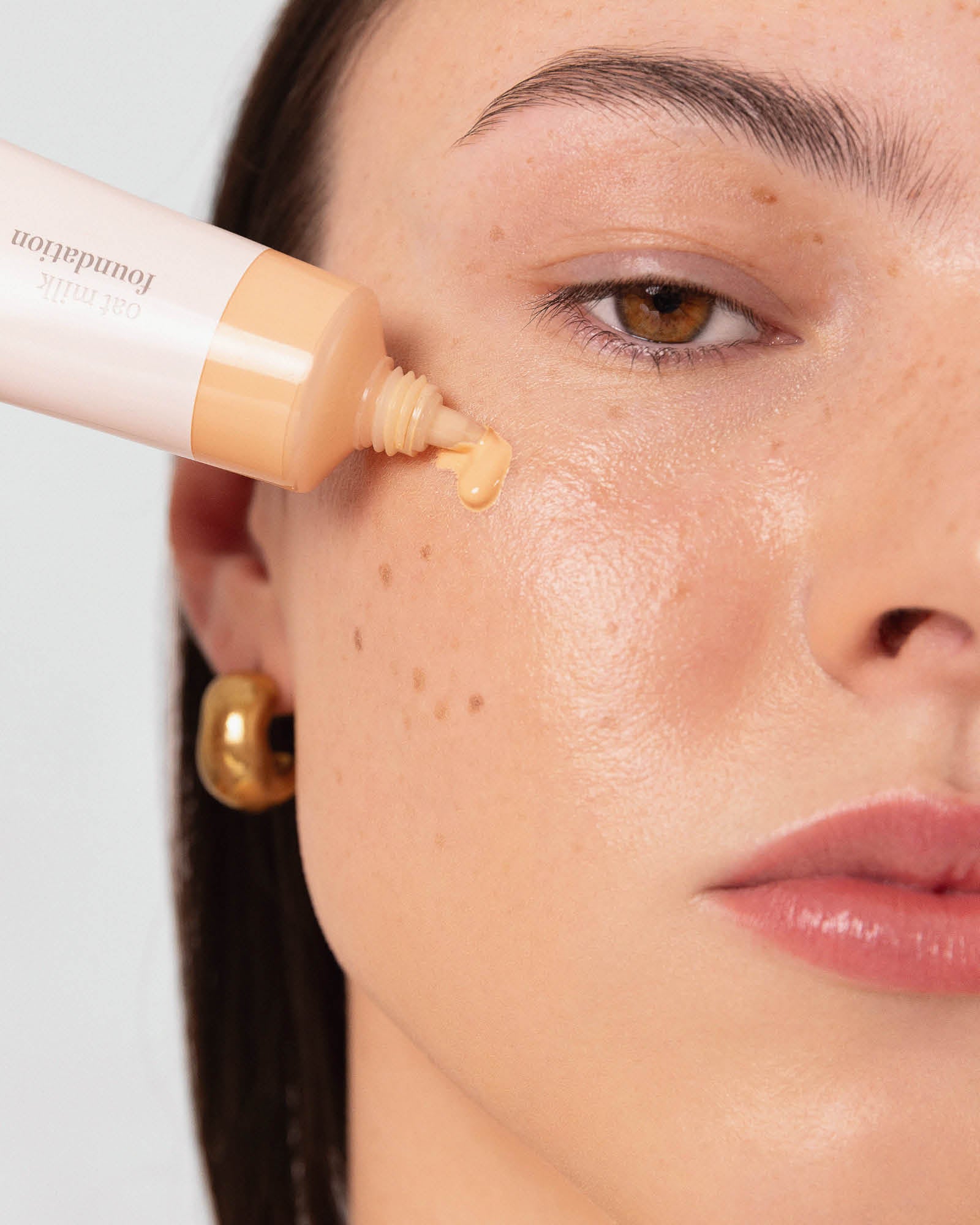 Person applying foundation to their face with a cosmetic bottle,