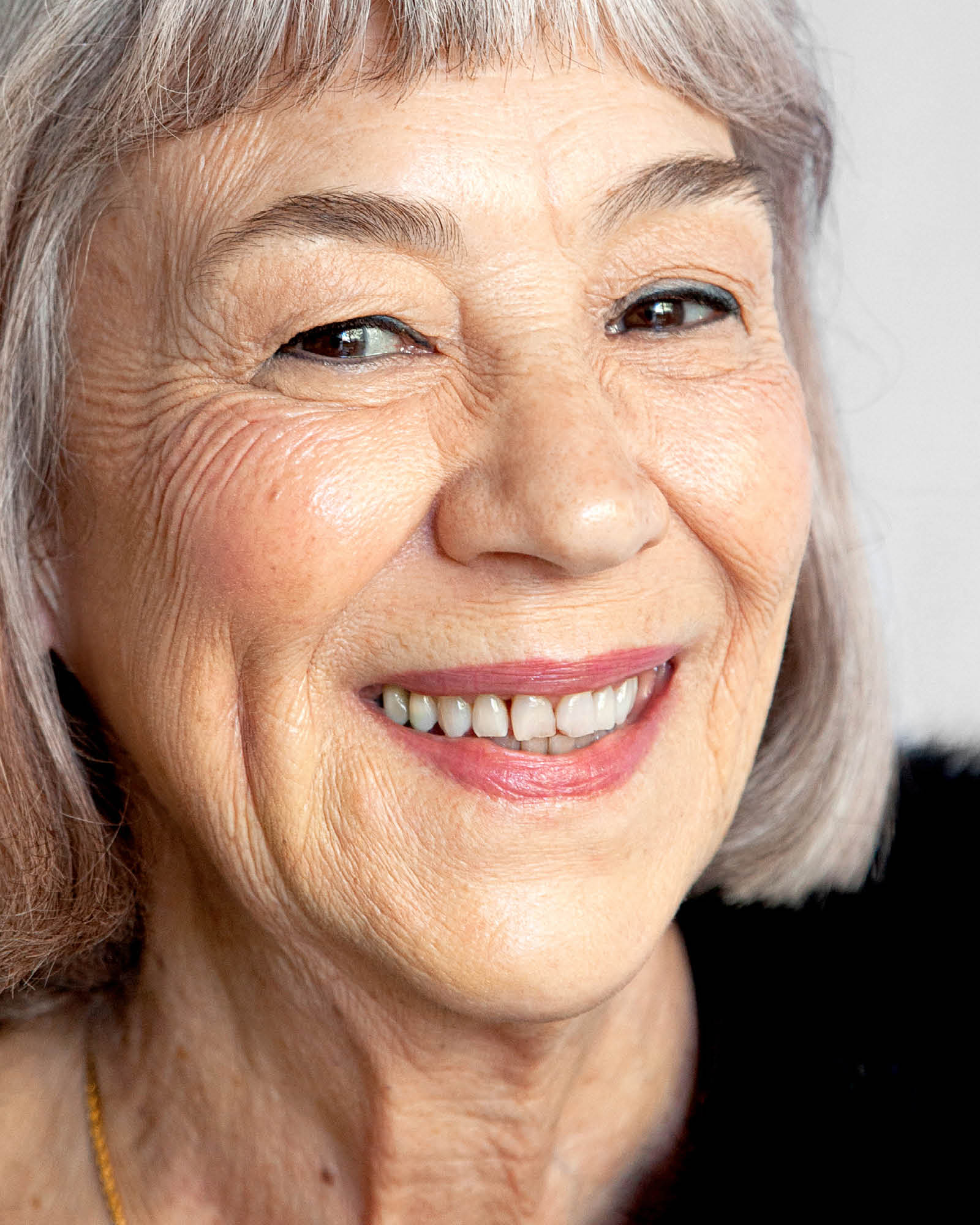Close-up of a smiling elderly woman with gray hair.,
