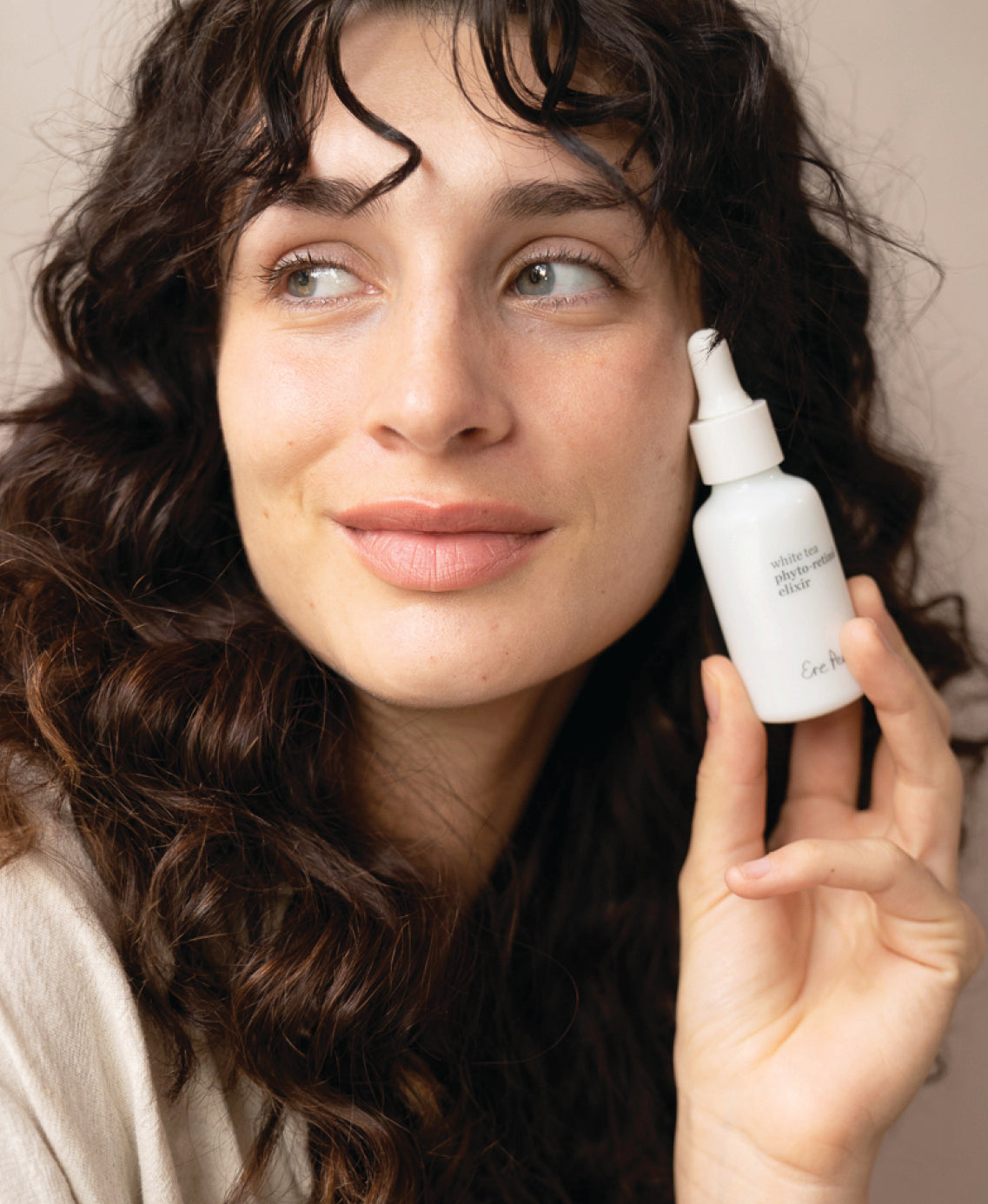 sustainable white tea phyto-retinol elixir by Ere Perez in its glass bottle and applied on the skin |
