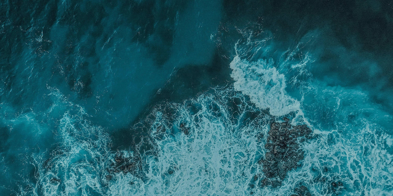 Aerial view of turquoise ocean waves crashing over rocks