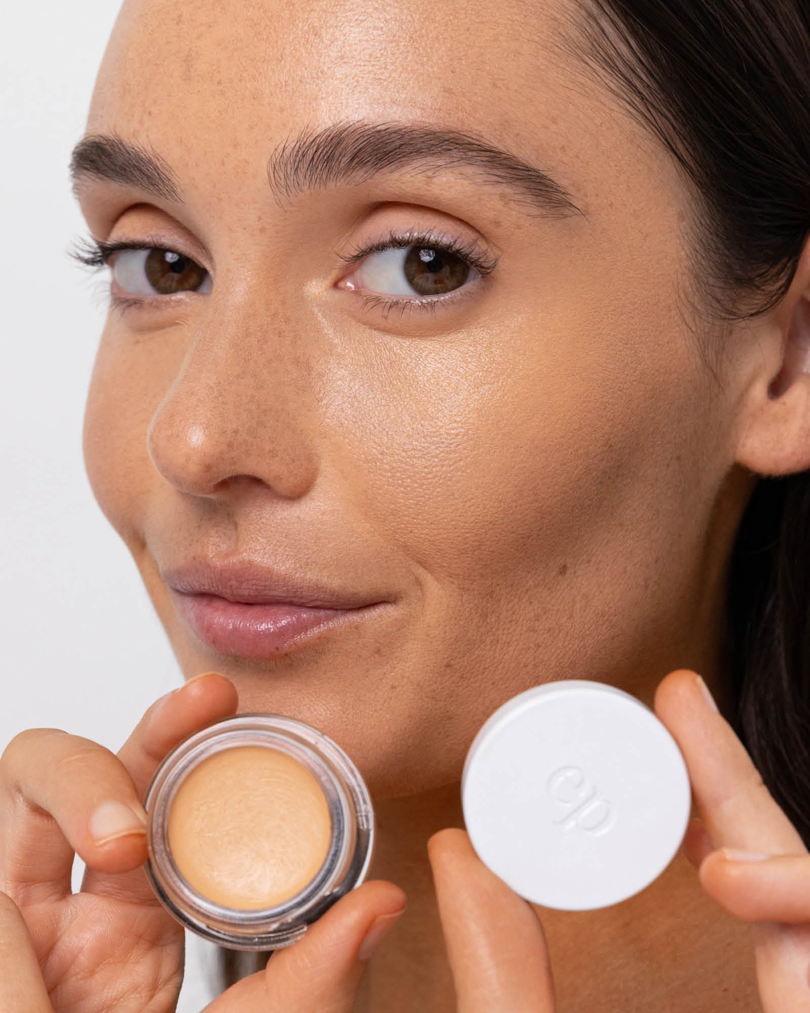 Person has applied Arnica All Cover Pot to their face with a close-up of the product. Arnica All Cover Pot in the shade caramel 