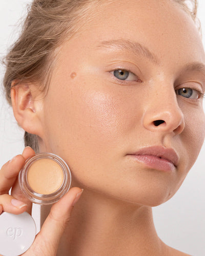 Person has applied Arnica All Cover Pot to their face with a close-up of the product. Arnica All Cover Pot in the shade chai 