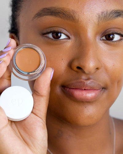 Person has applied Arnica All Cover Pot to their face with a close-up of the product. Arnica All Cover Pot in the shade mocha 