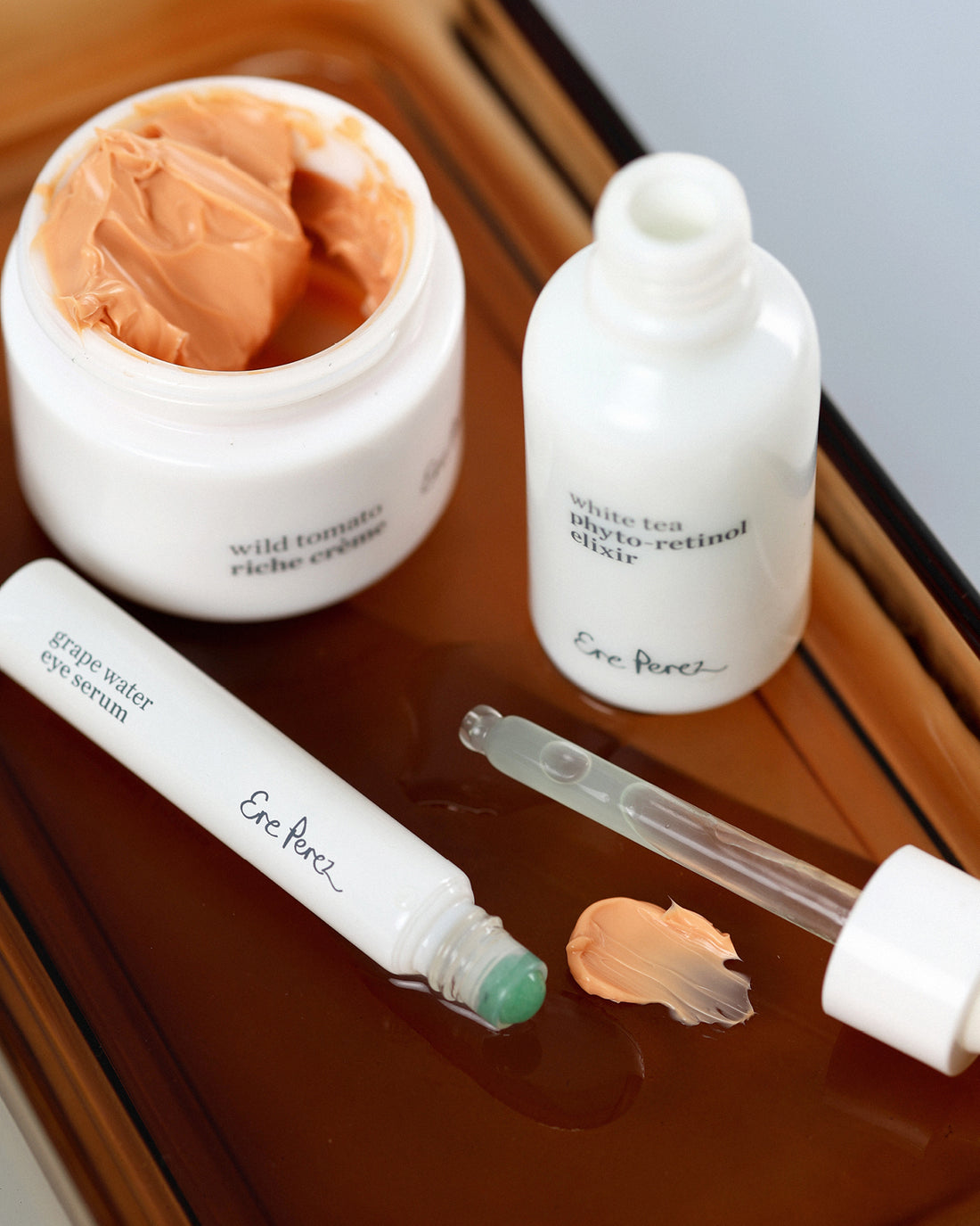 Radiance restore set and swatches by Ere Perez with white tea photo-retinol elixir bottle , grape water eye serum tube and wild tomato riche creme pot for moisturising anti-ageing effect