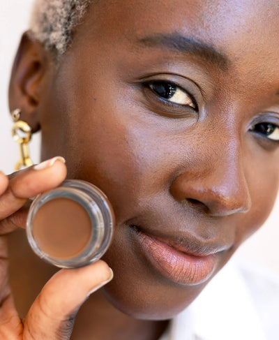 nourishing &amp; all-natural arnica concealer applied on skin and in pot by Ere Perez 