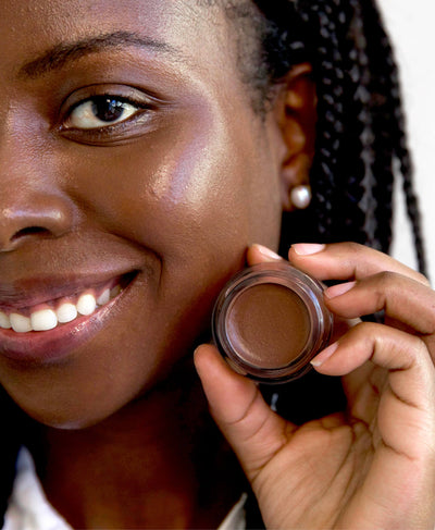 Delicate &amp; nourishing natural arnica concealer applied on skin and in pot by Ere Perez 