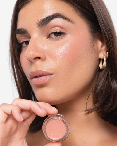 Person applying blush to their face with a close-up of the product. Carrot Colour Pot in Harmony 